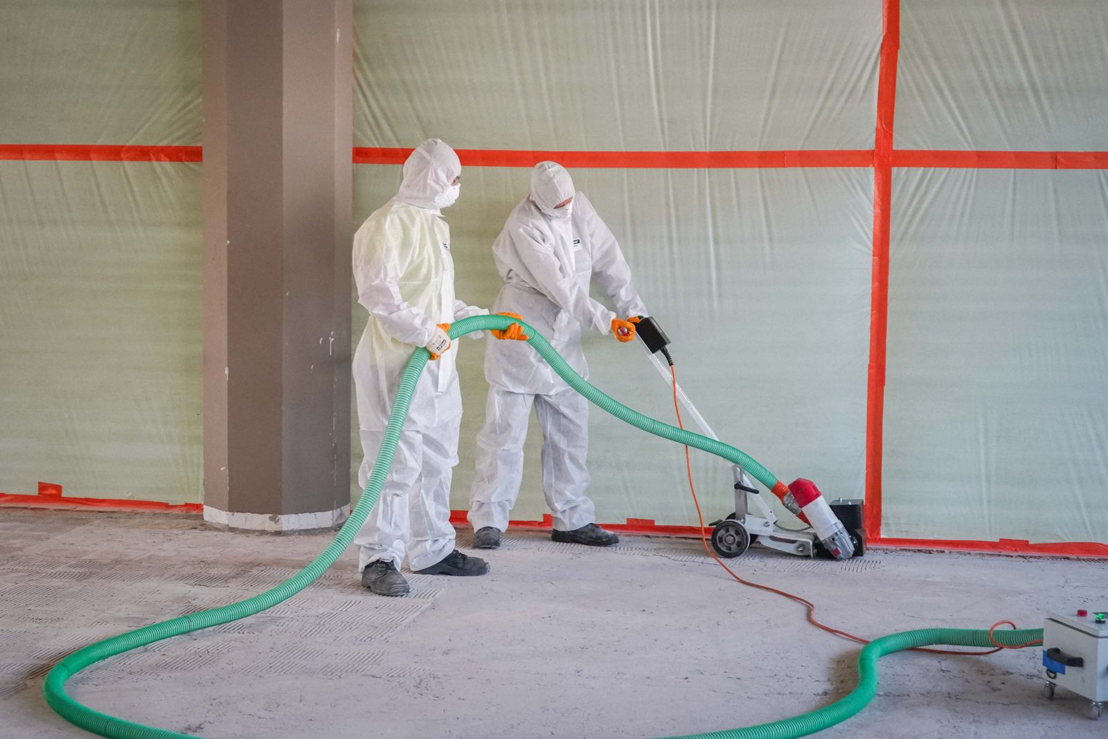 Zwei HSM-Mitarbeiter in Vollschutzanzügen mit Atemschutz bei der Bodensanierung im abgeschotteten Schwarzbereich