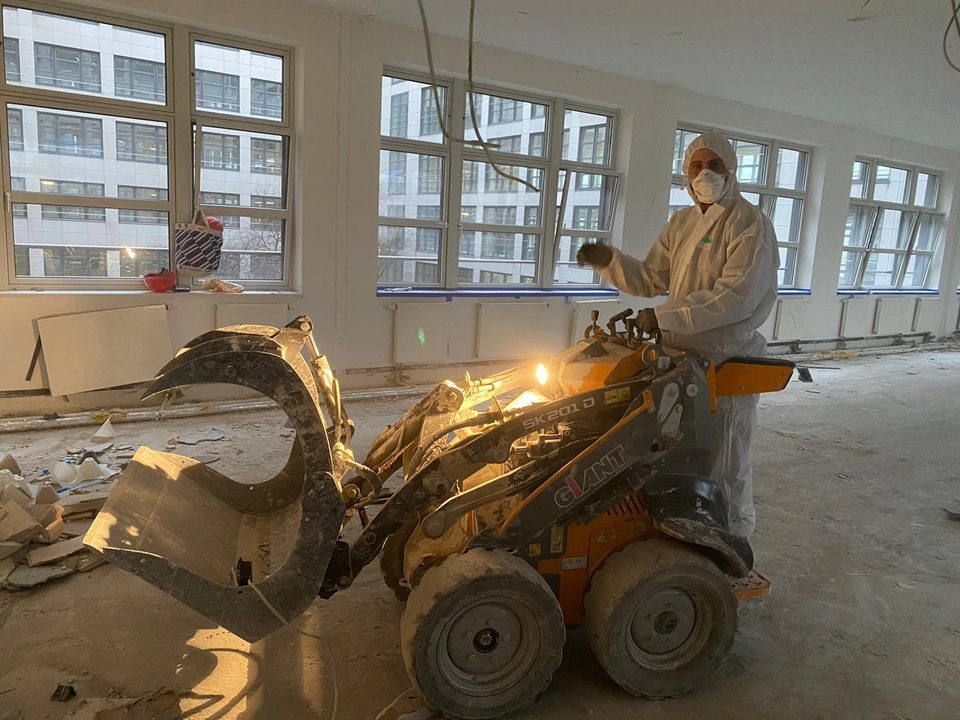 Arbeiter in Schutzanzug bedient einen Radlader mit Greifer beim Innenrückbau