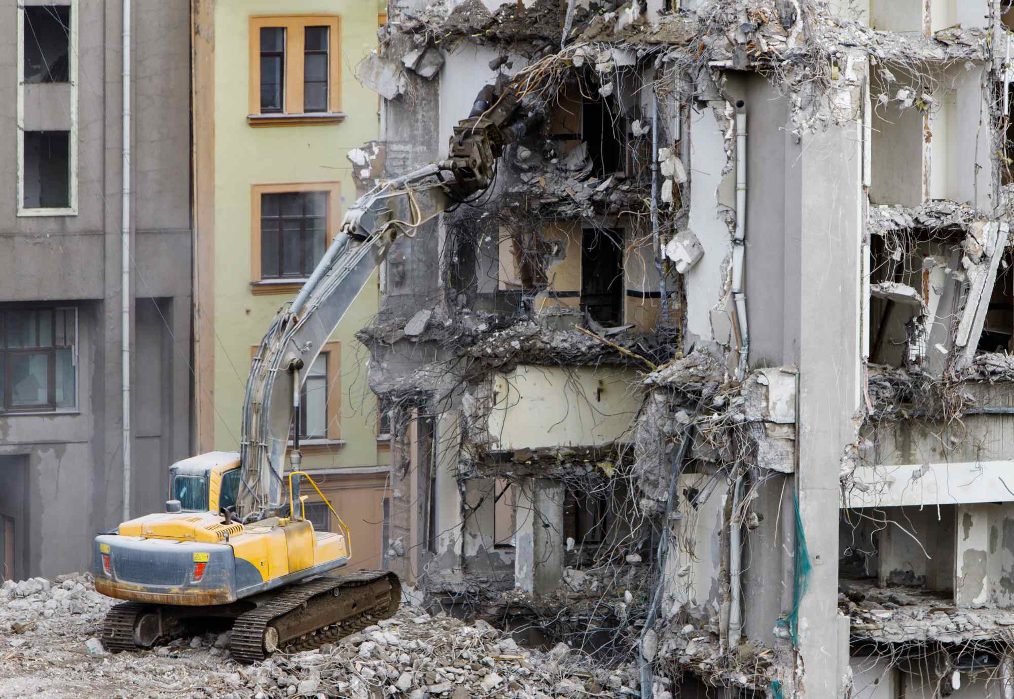 Building of the former hotel demolition for new construction, using a special hydraulic excavator-destroyer. Complete highly mechanized demolition of building structures. Construction site concept